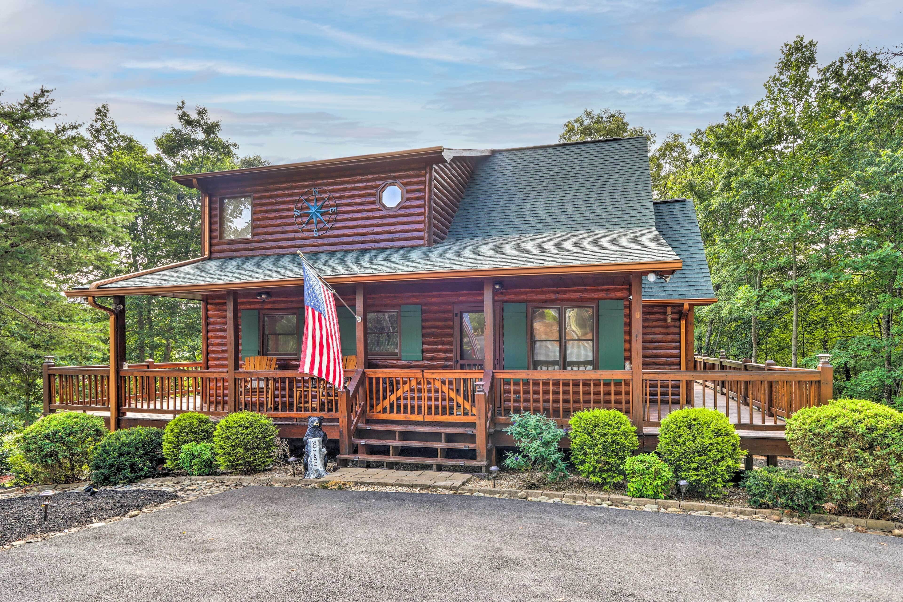 A log cabin with a porch, American flag, and a windmill.
