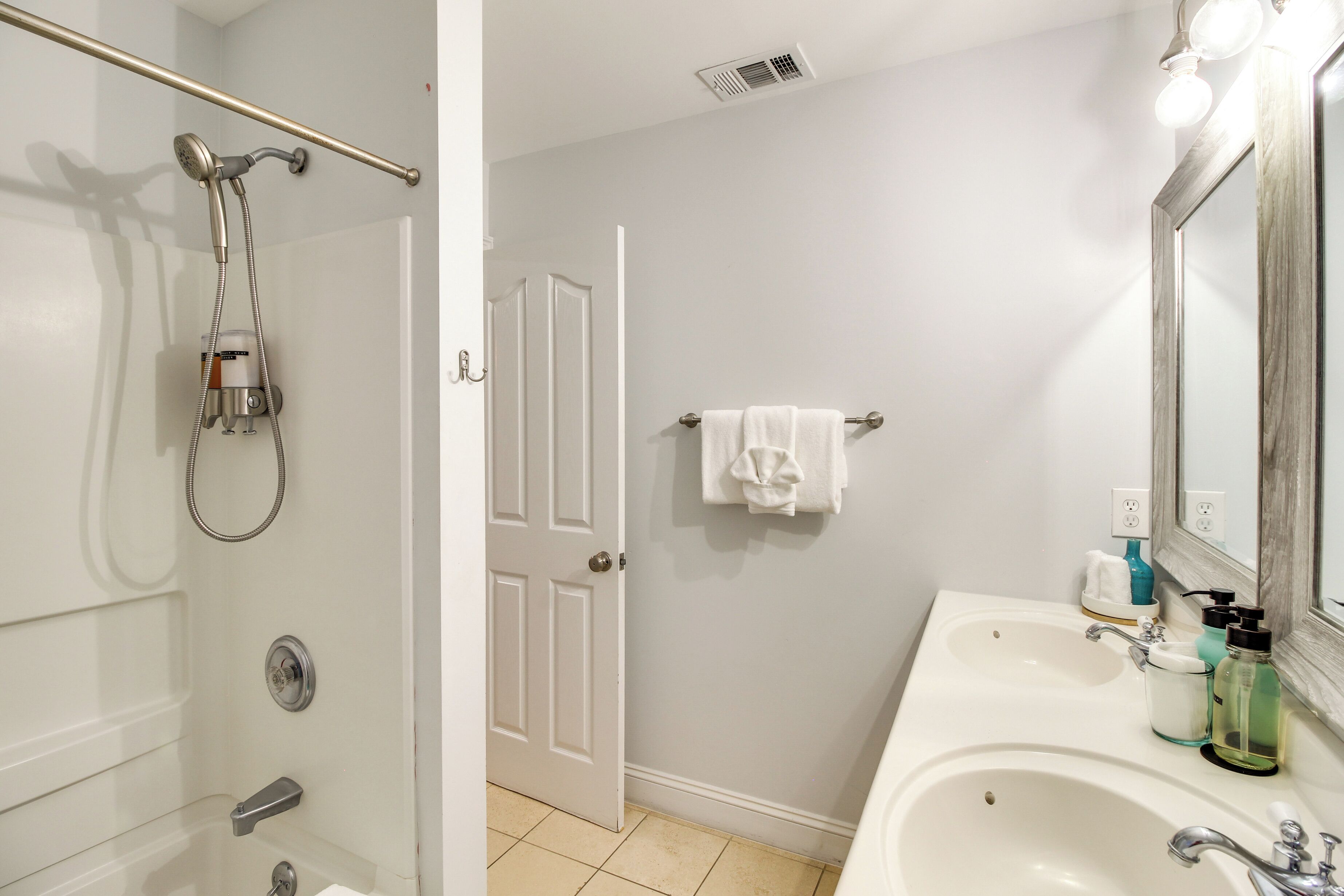 A bathroom with a shower, a sink, a mirror, and a towel rack.