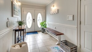 A hallway with a bench, a potted plant, a basket, and a door with glass panels.