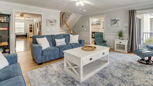 A spacious living room with a blue sofa, white coffee table, and a staircase leading to another level.