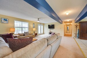 Una sala de estar con un sofá modular color beige, una lámpara y un televisor.