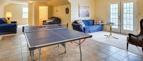Un salon spacieux équipé d’une table de ping-pong, de sièges confortables et d’une grande fenêtre laissant entrer la lumière naturelle.