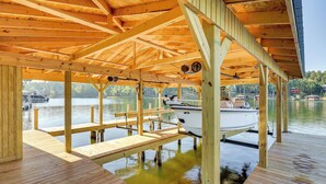 A wooden dock with a covered seating area and a boat moored nearby.