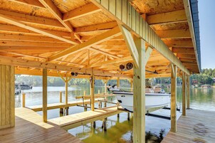 Un muelle de madera con un área de estar techada y un barco amarrado cerca.