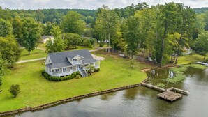 A house with a large deck, a dock, and a pond.