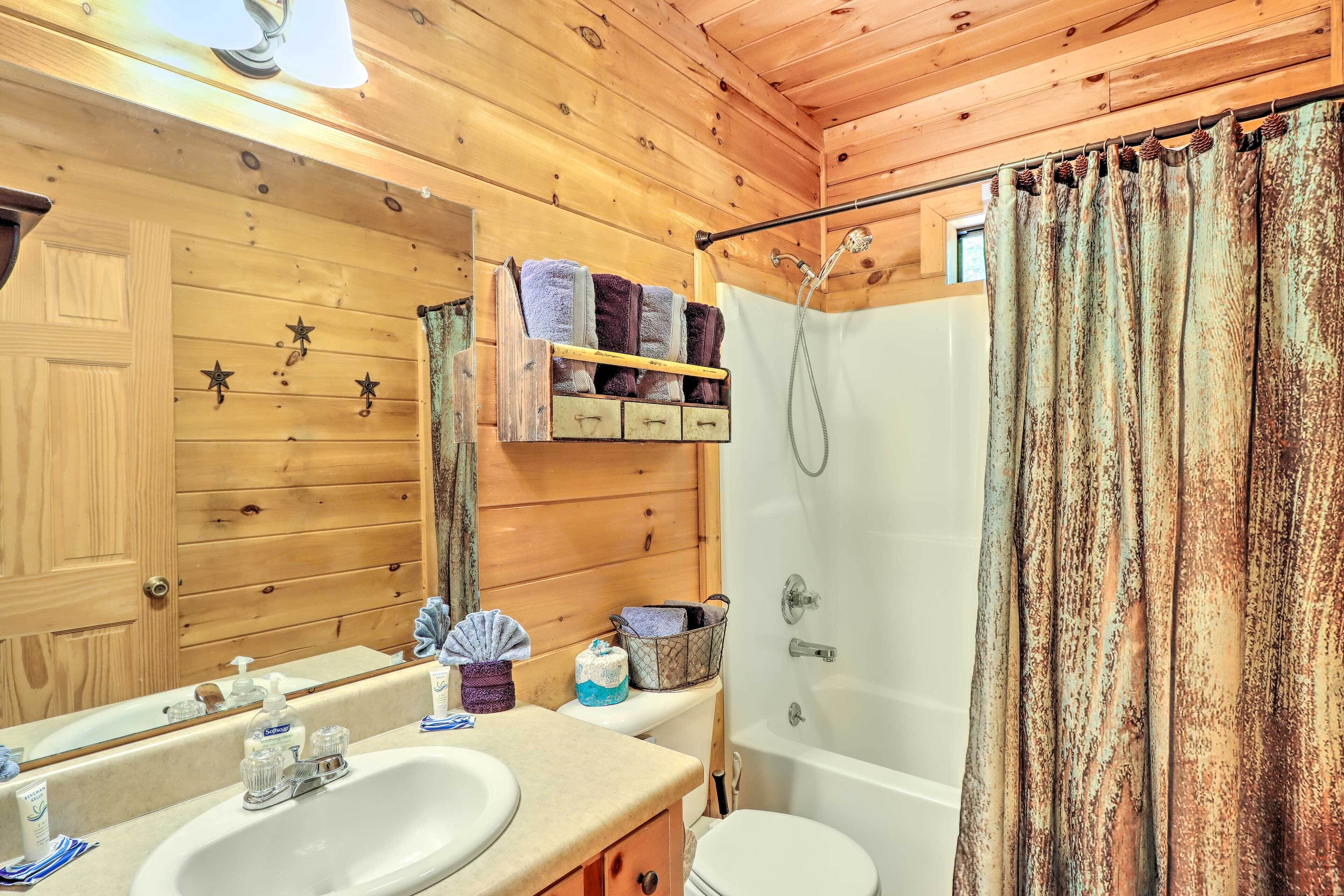 A wooden cabin bathroom with a sink, mirror, and shower.
