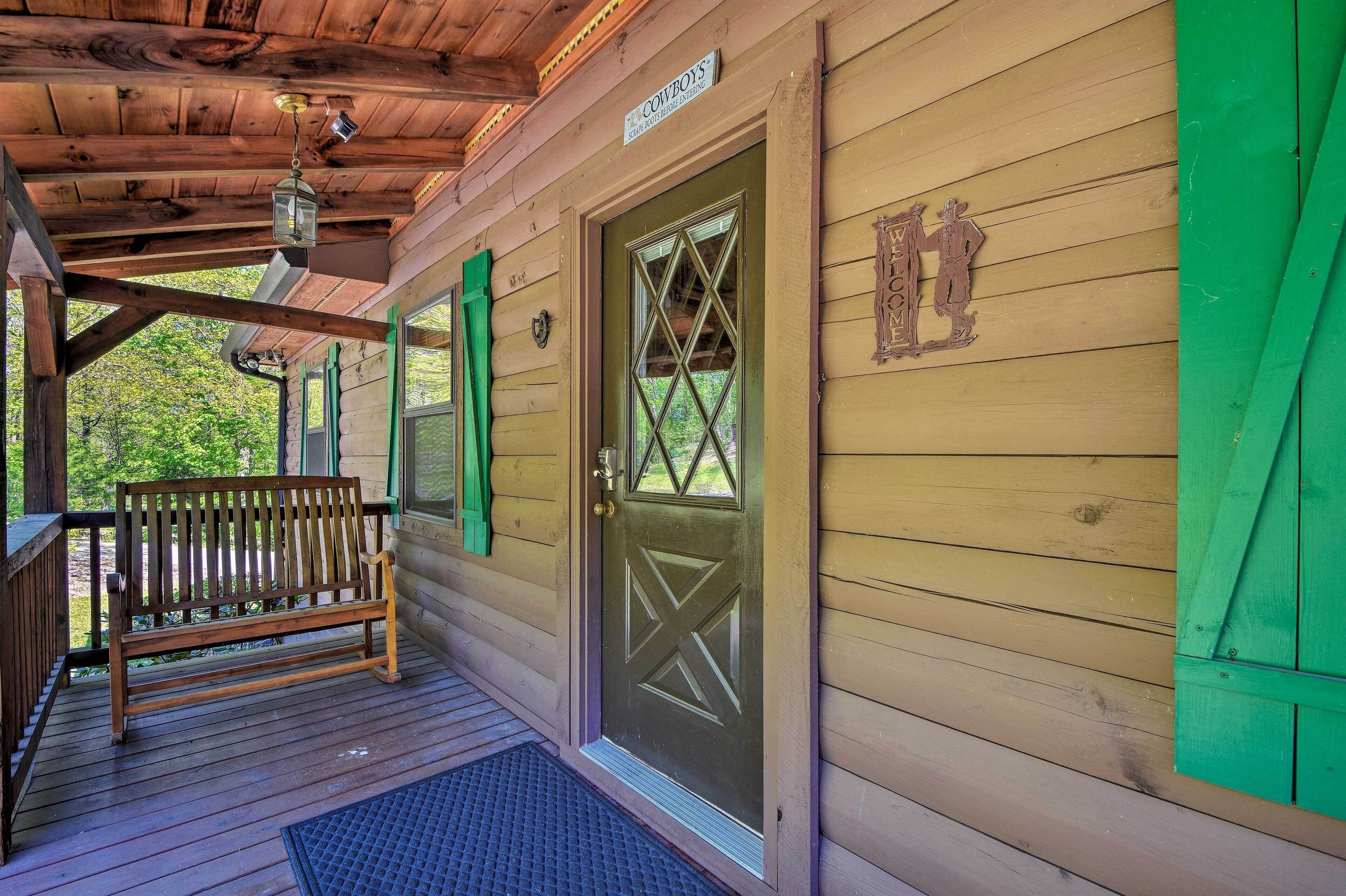 Eine Holzhütte mit Veranda, einer Bank und einer Tür mit einem dekorativen Fenster.