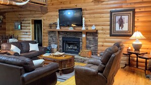 A cozy log cabin interior with a fireplace, leather furniture, and a television mounted above it. - Cozy Trenton Cabin w/ Spa ~ 15 Mi to Lookout Mtn! (Trenton)