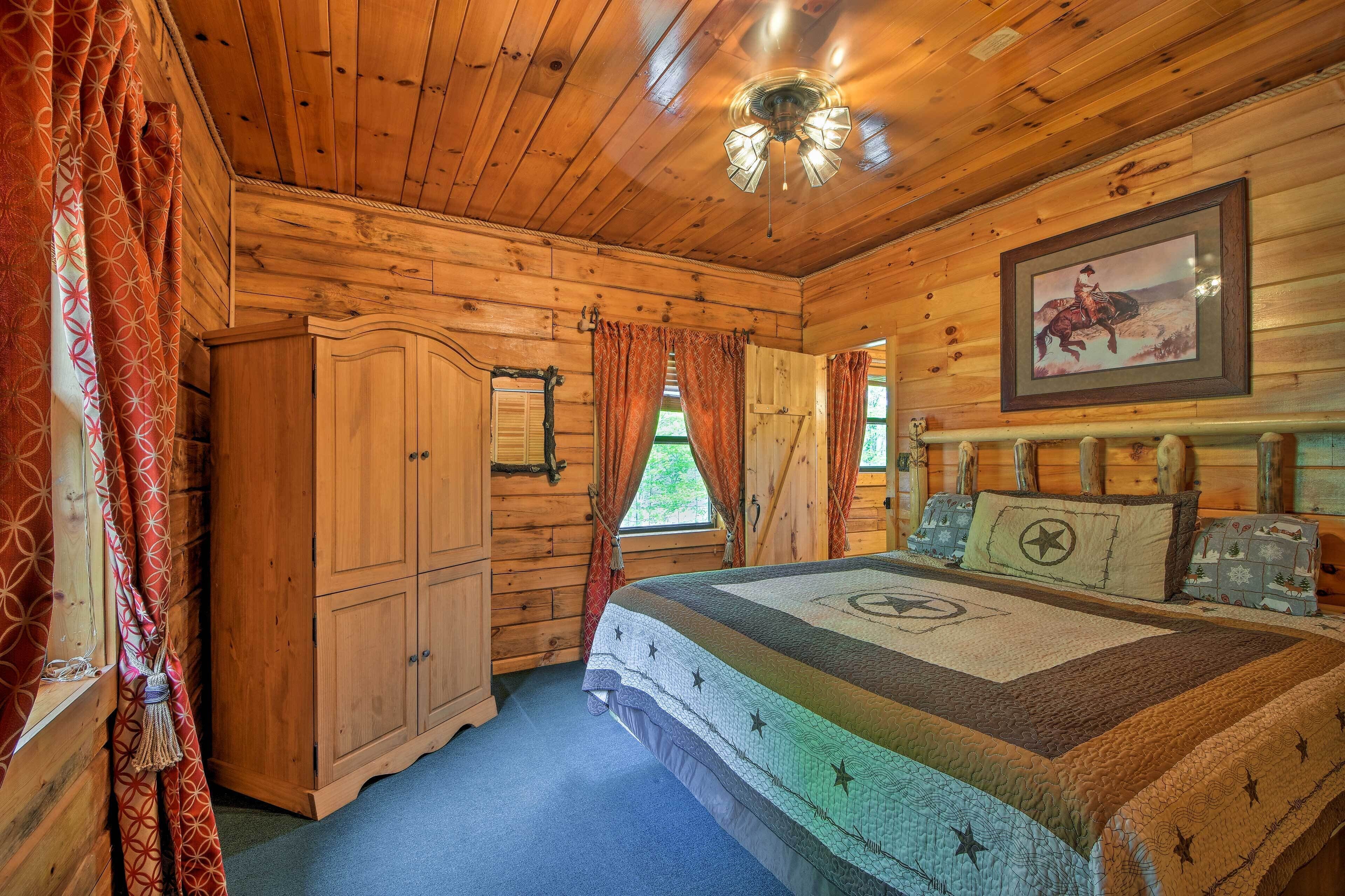 Une chambre dans une cabane en bois, avec un lit, des rideaux, une armoire et un ventilateur de plafond.