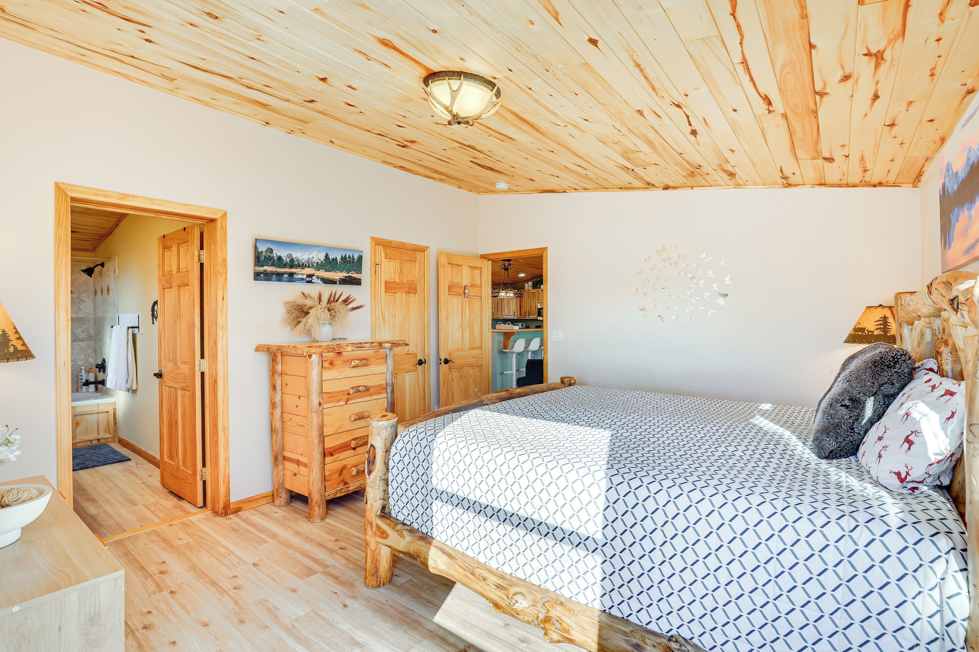 Une chambre avec un plancher en bois, comprenant un lit, une armoire en bois et une porte donnant sur une salle de bain.