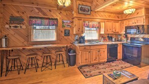 A wooden cabin interior with a kitchen, bar area, and seating.