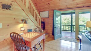 L’intérieur d’un chalet en bois comprend une table à manger, des chaises, une carte accrochée au mur et un escalier menant à une terrasse.