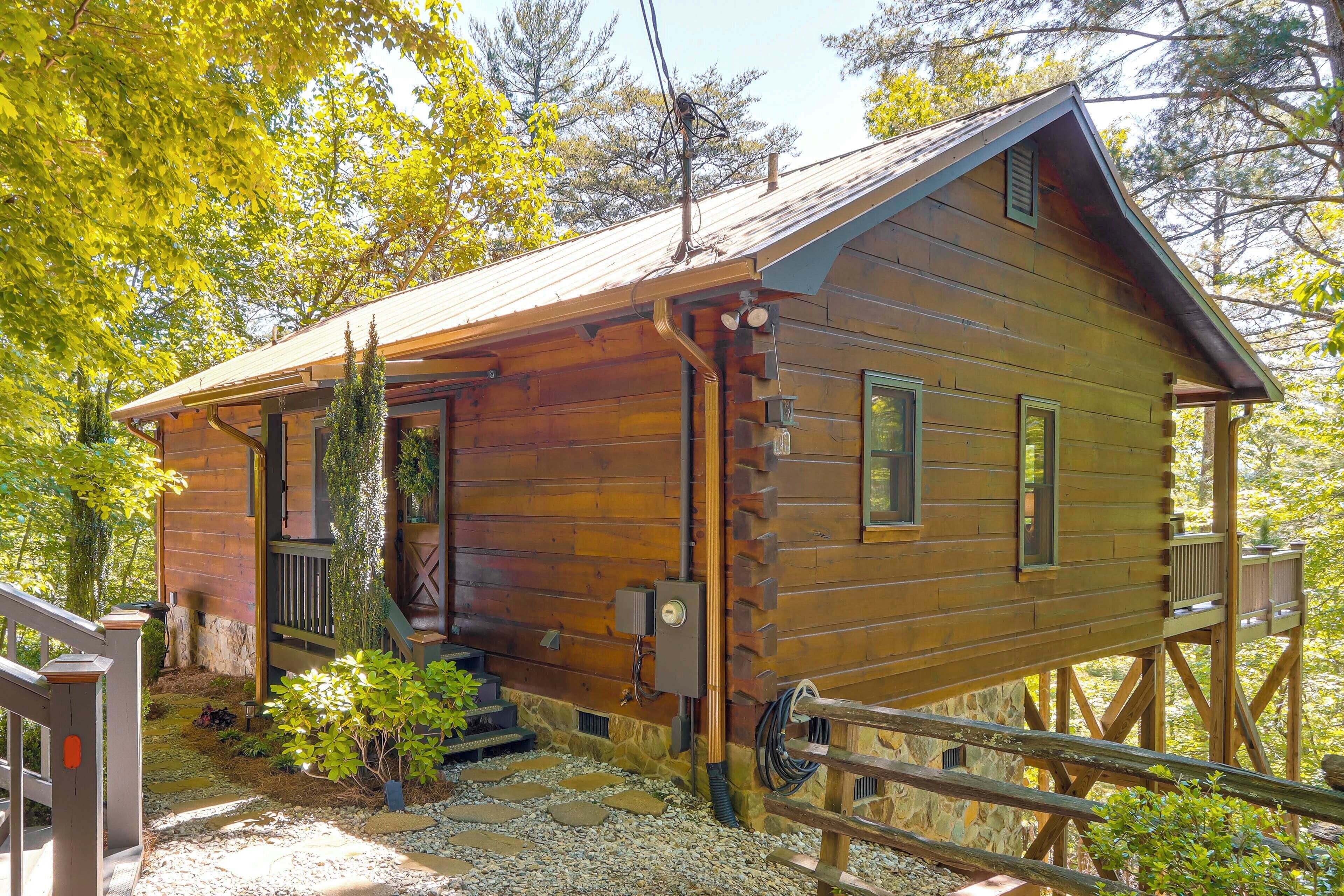 A wooden cabin with a sloped roof, a small porch, and a stone foundation.