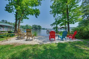 Un espace de détente aménagé au bord du lac, avec des chaises Adirondack et une table de pique-nique couverte.