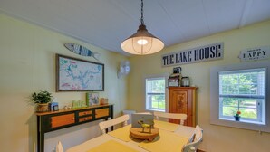 Ein Essbereich mit einem Tisch, Stühlen, einer Karte, einer Lampe und einem Schild mit der Aufschrift 'THE LAKE HOUSE'.