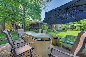 An outdoor patio with a dining table, chairs, and a large umbrella. - Lake Sinclair 'crooked Creek Cottage' w/ Fire Pit! (Eatonton)