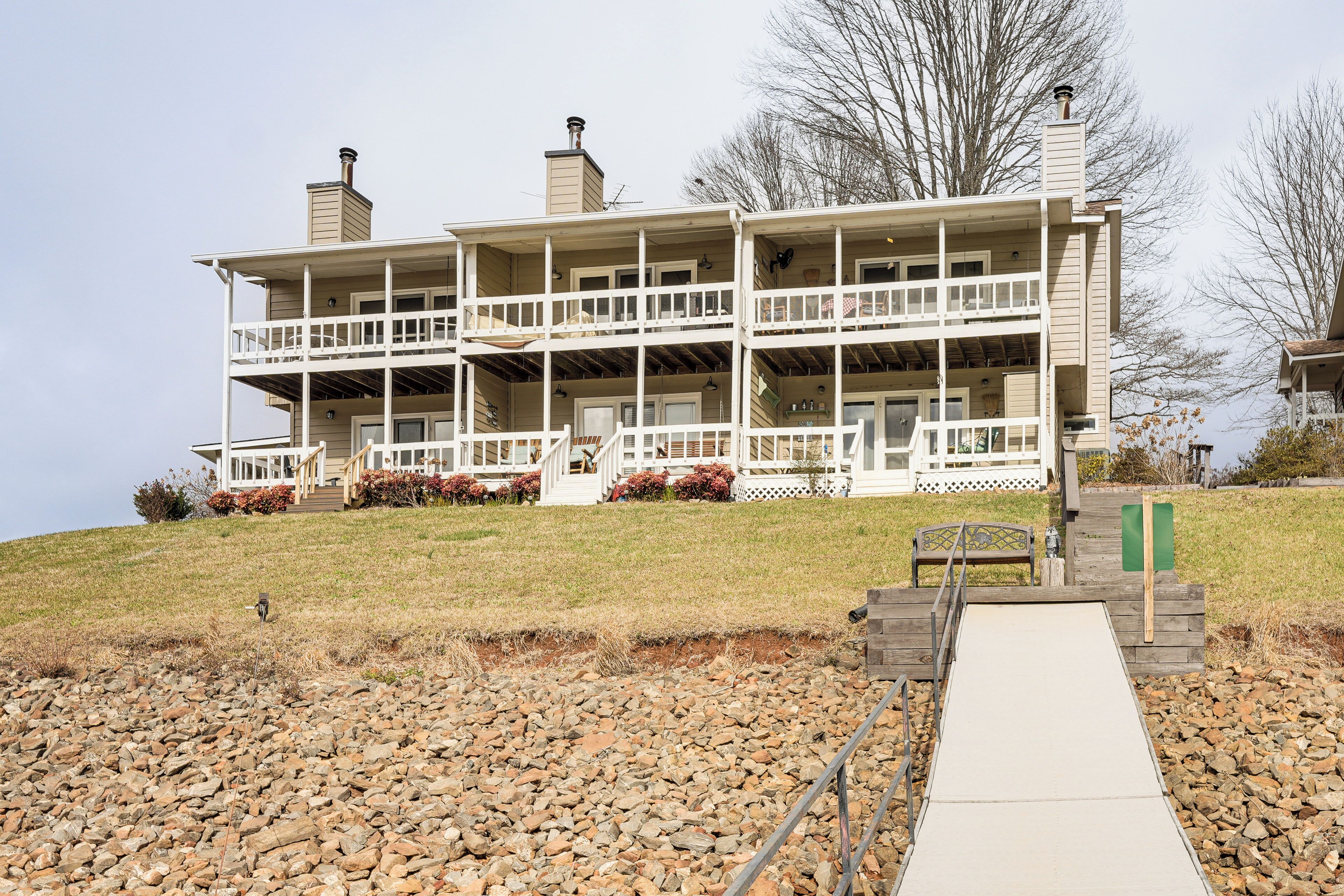 A two-story building with a balcony on the ground floor, a covered porch, and a pathway leading to the entrance.