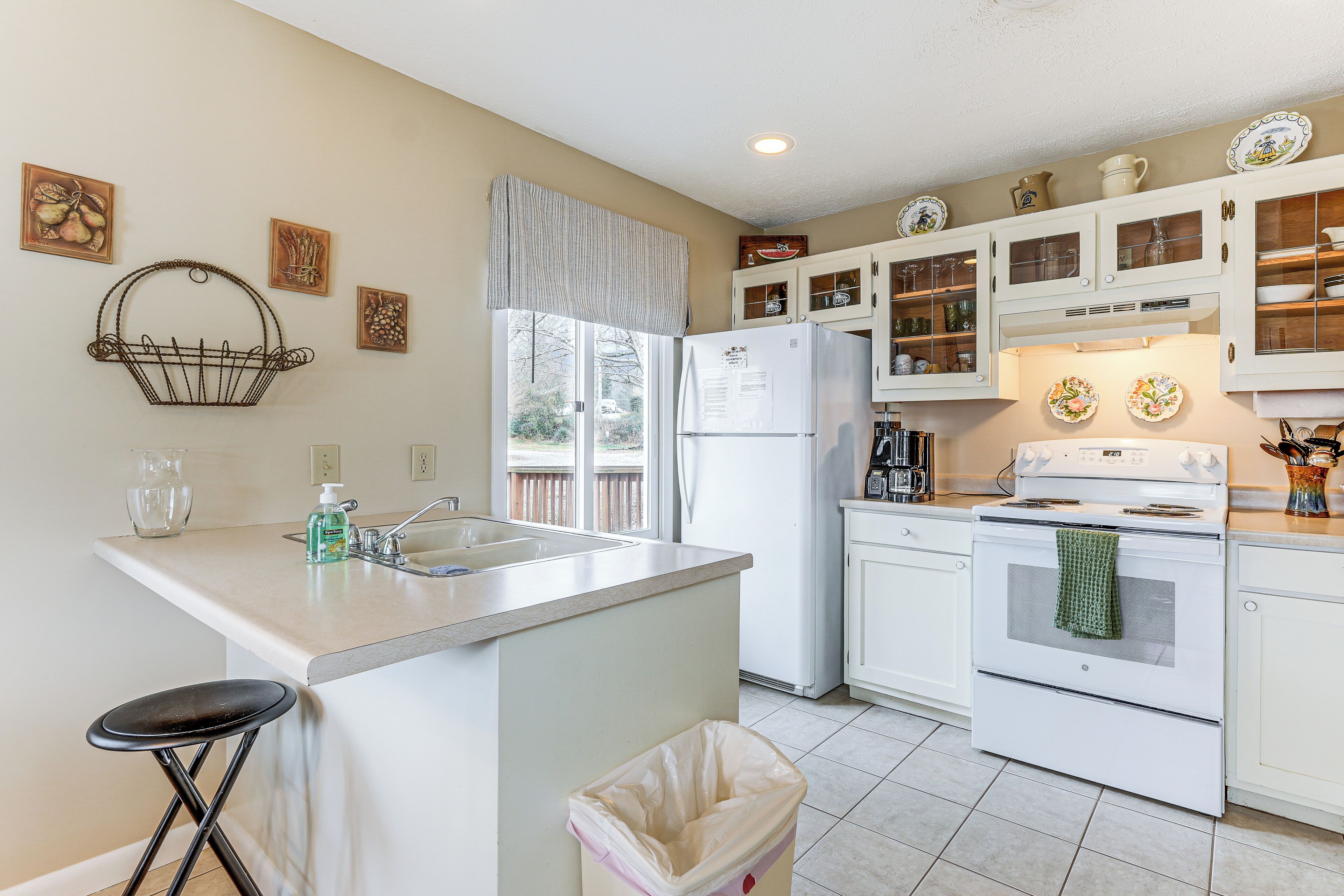 A kitchen with a central island, white cabinets, a refrigerator, and a stove.