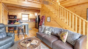 A cozy cabin interior with a wooden staircase, a dining area, and a living room with a leather sofa and a coffee table. - Lake Blue Ridge Cabin by the Chatahoochie Forest (Blue Ridge)