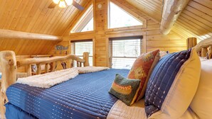 A log cabin bedroom with a large bed, a ceiling fan, and two windows. - Lake Blue Ridge Cabin by the Chatahoochie Forest (Blue Ridge)