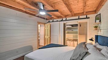 Un dormitorio con una cama, un ventilador de techo, un armario y una estantería con una planta.