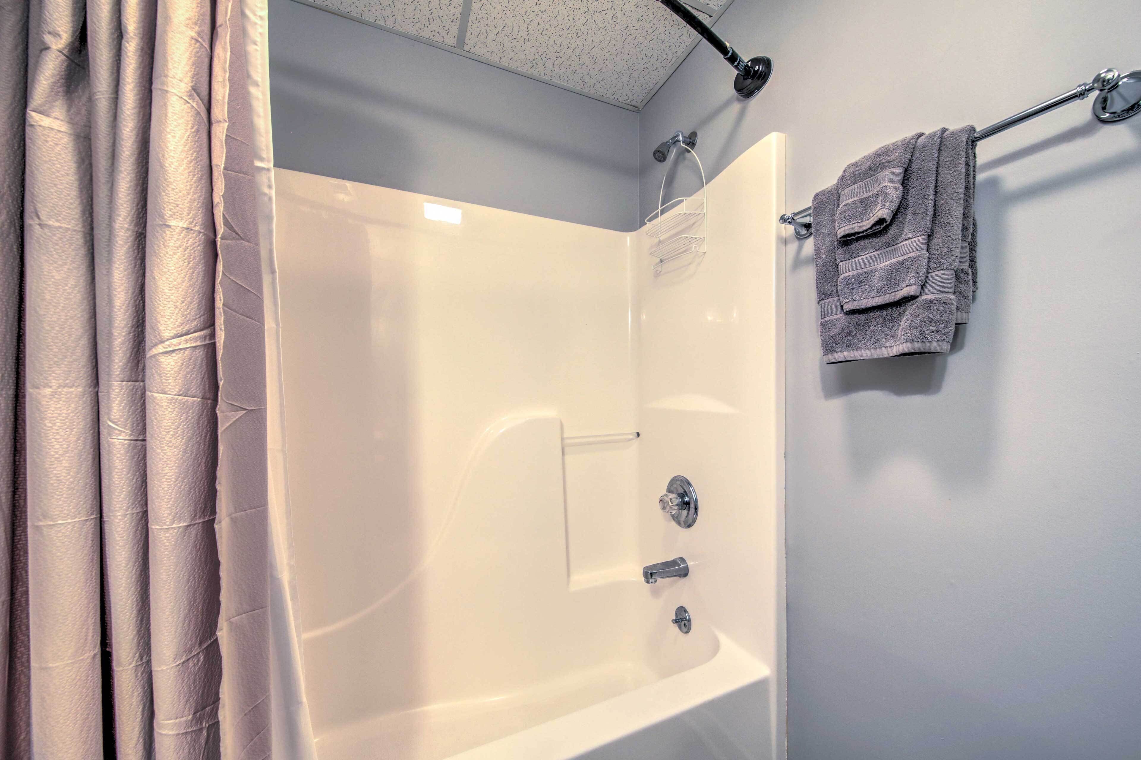 A bathroom with a bathtub, a shower, and a towel rack.