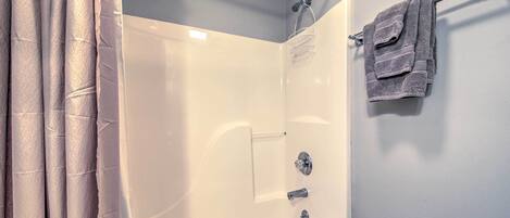 A bathroom with a bathtub, a shower, and a towel rack.