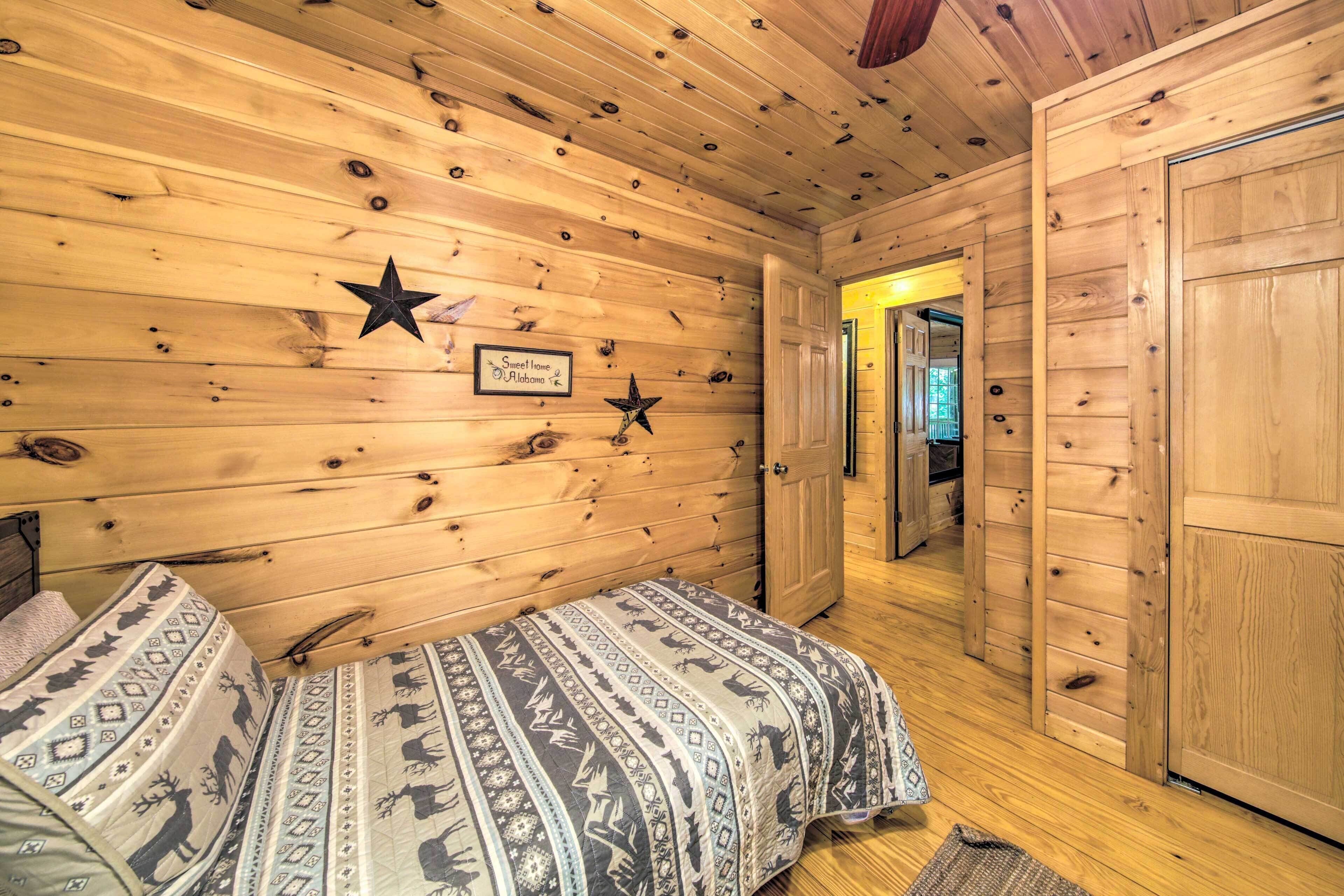 A wooden cabin interior with a bed, a star decoration, and a sign that reads 'Sweet Home Alabama.'