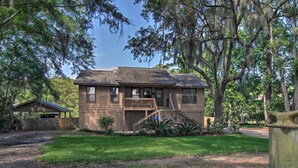 A two-story wooden house with a front porch, a small garage, and a well-maintained lawn.