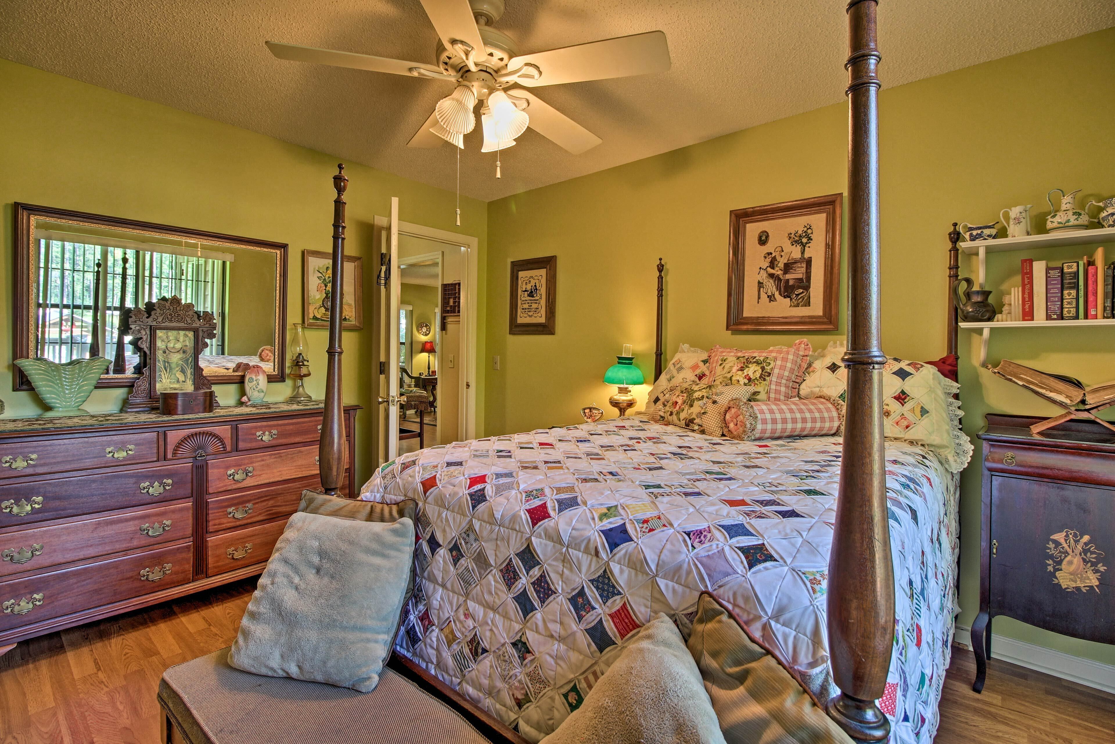 A bedroom with a four-poster bed, a wooden dresser, a mirror, and a bookshelf.