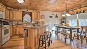 Una cocina rústica con armarios de madera, una isla central, taburetes de bar y una mesa de comedor con bancos.