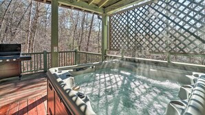 Un jacuzzi en una terraza de madera con vista a un bosque.