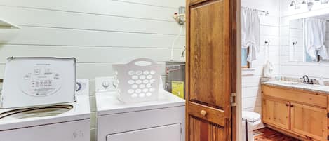 Un área de lavandería con lavadora, secadora y una puerta de madera que da a un baño.