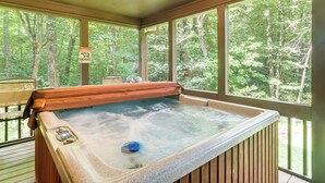 A hot tub with a wooden edge, surrounded by large windows offering a view of a forested area. - Creek Front Cabin w/ Hot Tub+fire Pit (Blue Ridge)