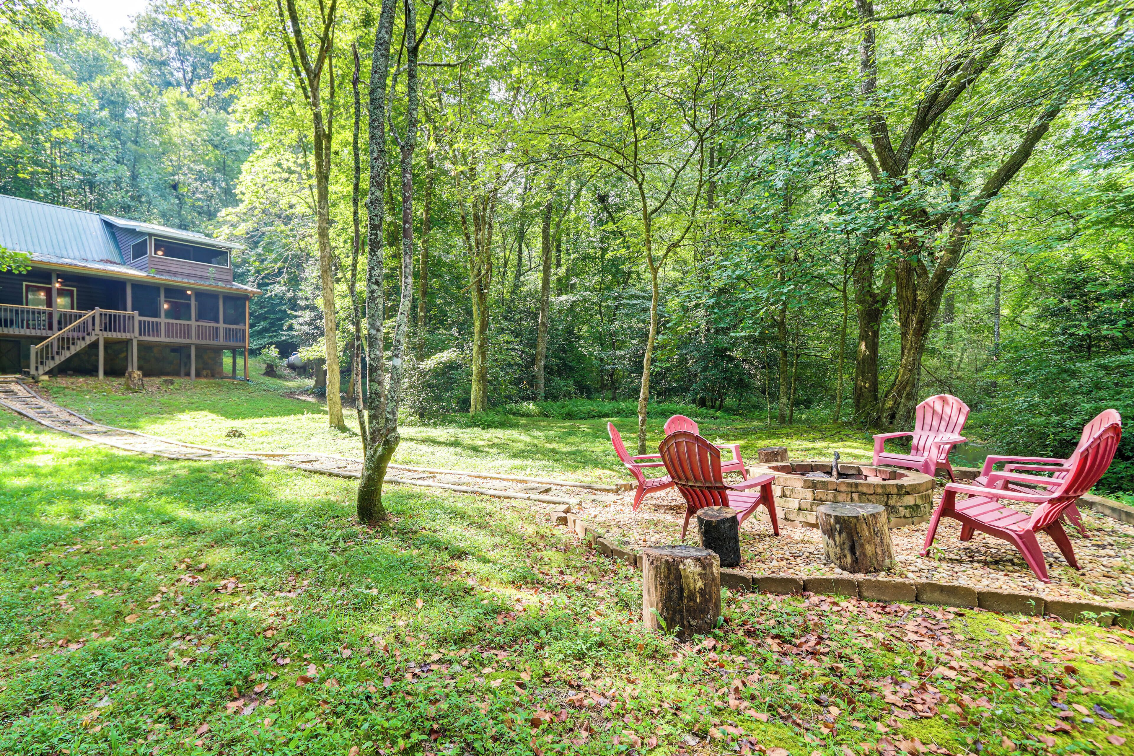 A cabin with a deck and a fire pit area with chairs.