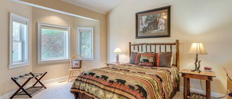 A bedroom with a large bed, two bedside tables with lamps, a ceiling fan, and a framed picture on the wall.