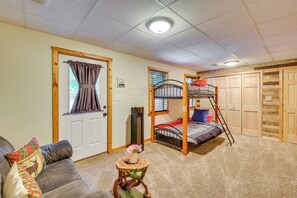 A cozy room with a bunk bed, a sofa, a small table with a flower, and a door with curtains. - Spacious Cabin w/ Deck + Hot Tub in Blairsville (Blairsville)