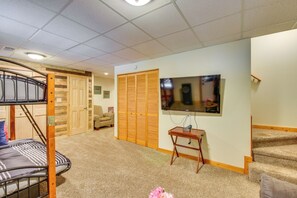 A room with a bunk bed, a television mounted on the wall, a wooden closet, and a carpeted floor. - Spacious Cabin w/ Deck + Hot Tub in Blairsville (Blairsville)