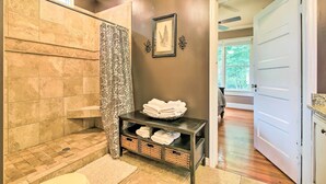 A bathroom with a shower, a vanity with a sink, and a towel rack.