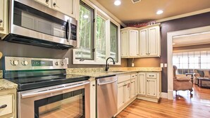 A kitchen with stainless steel appliances, white cabinetry, and a wooden floor.