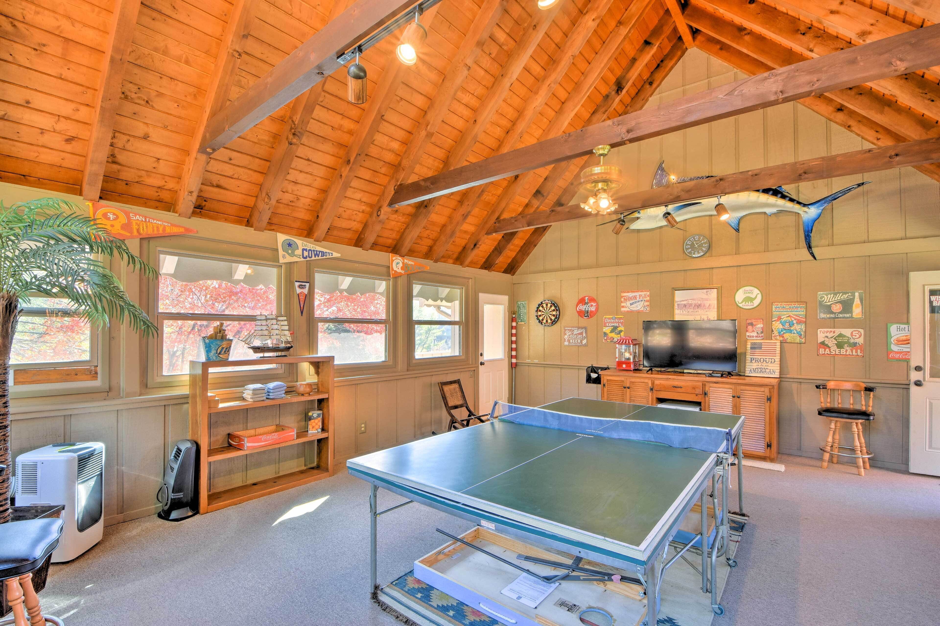 Une pièce équipée d’une table de ping-pong, d’un téléviseur et ornée de divers objets de collection accrochés aux murs.