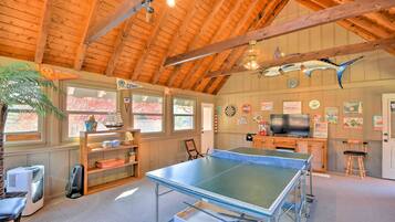 Une pièce équipée d’une table de ping-pong, d’un téléviseur et ornée de divers objets de collection accrochés aux murs.