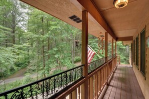 A wooden porch with a view of a forested area.