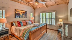 A bedroom with a wooden bed, a ceiling fan, and a painting on the wall.