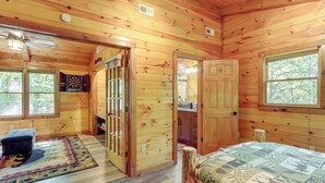 Ein Holzblockhaus mit einem Bett, einer Bank, einer Tür und einem Fenster.