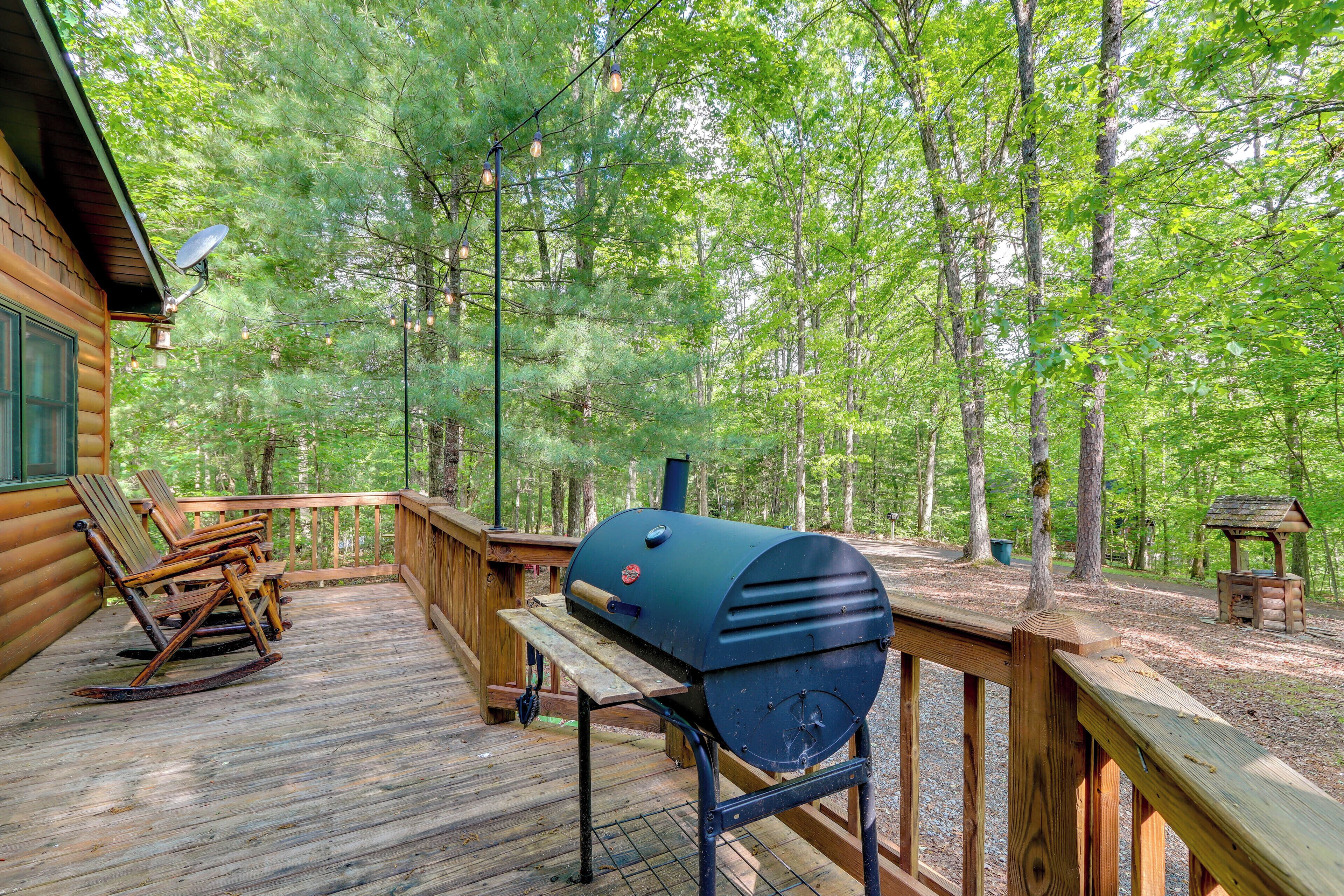 A wooden deck with a barbecue grill, rocking chairs, and a picnic table.
