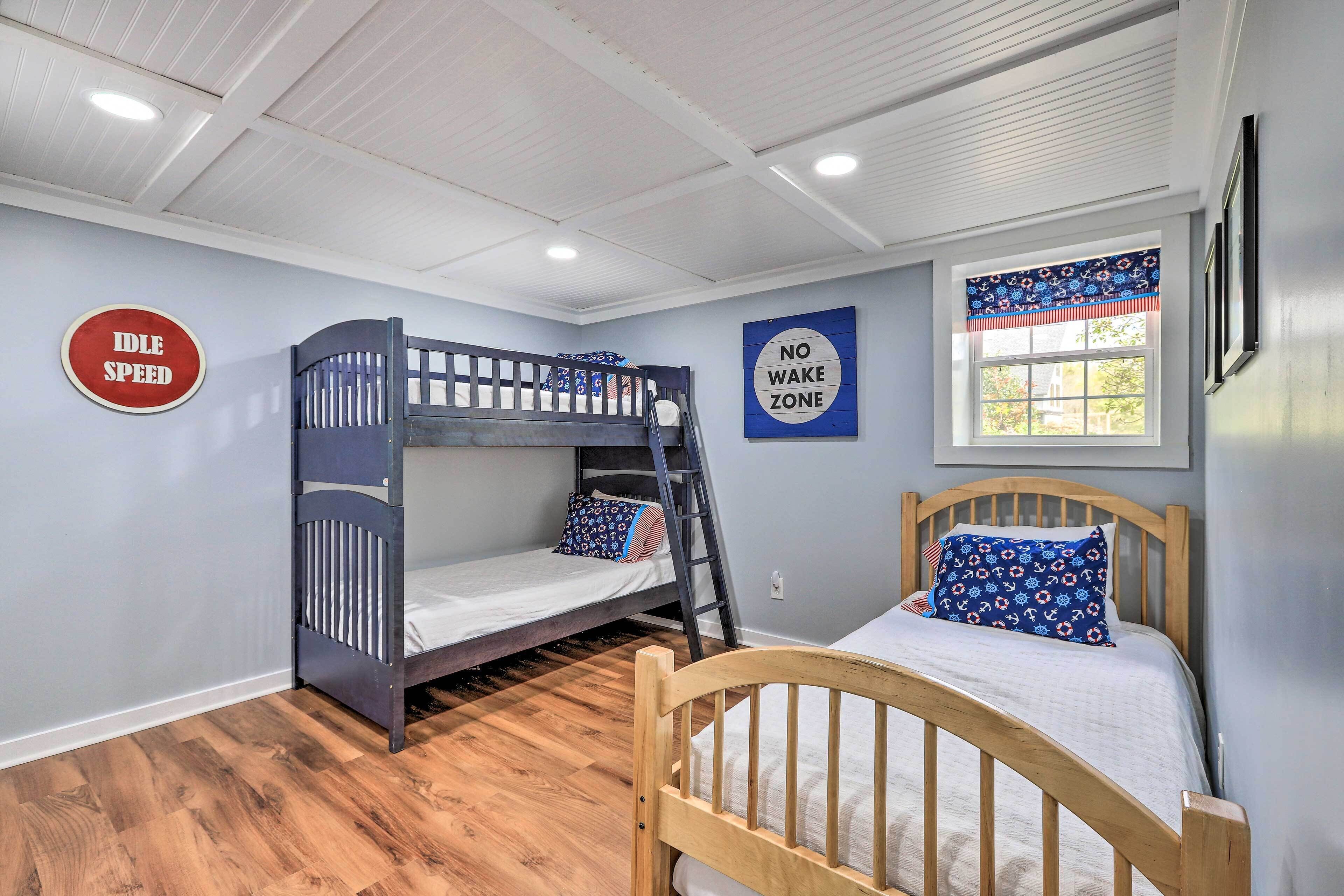 Une chambre avec des lits superposés, une échelle, une fenêtre avec des rideaux et deux panneaux décoratifs accrochés au mur.