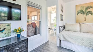 Ein Schlafzimmer mit einem Bett, einer Kommode, einem Fenster mit Jalousien und einem Vogelgemälde.