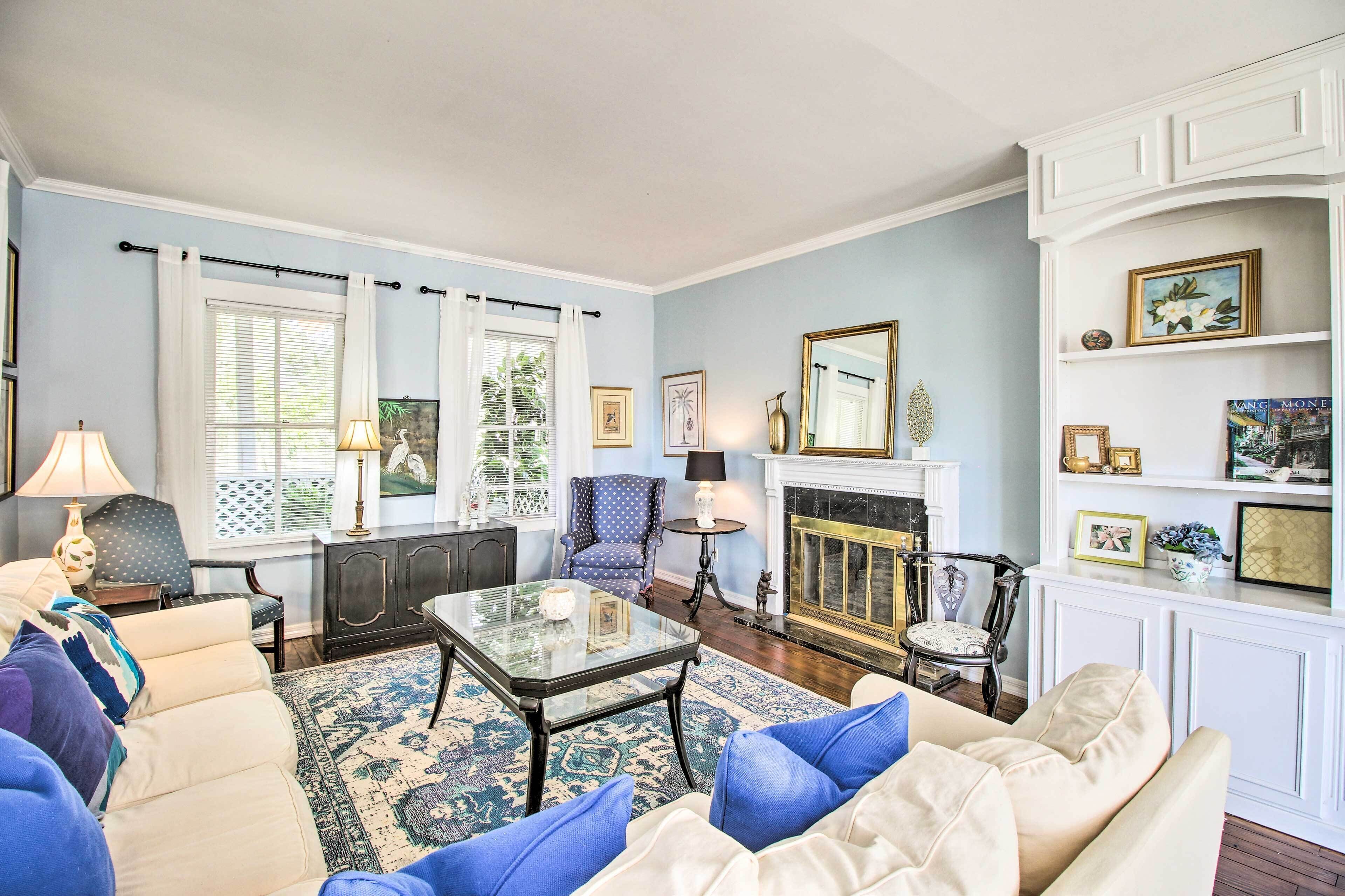 A living room with a sofa, armchairs, a coffee table, a fireplace, and a bookshelf.