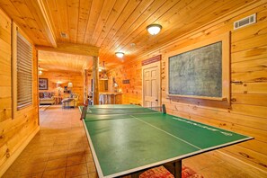 Uma mesa de pingue-pongue em um quarto de madeira, com um quadro negro e uma porta.